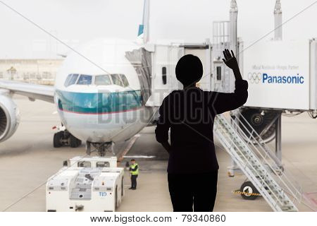 Silhouette Of A Woman Waving Goodbye To An Airplane