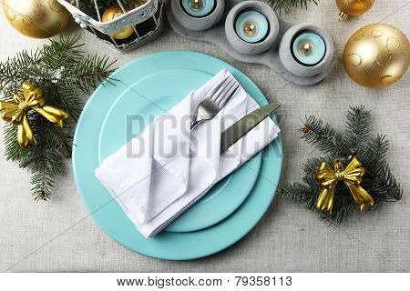Christmas table setting in blue, golden and whitec olors on grey tablecloth background