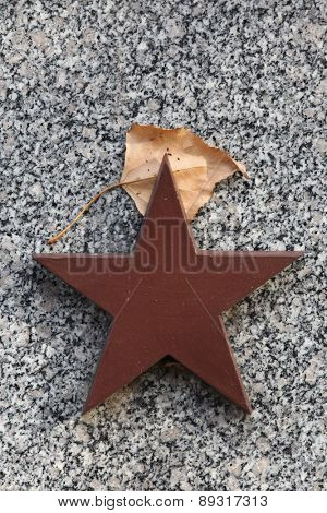 Red star and autumn birch leaf at the Soviet War Memorial with graves of Soviet soldiers fallen in the last days of World War II at the Olsany Cemetery in Prague, Czech Republic.