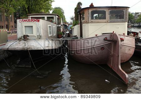 AMSTERDAM, NETHERLANDS - AUGUST 8, 2012: Two houseboats moored on the Amstel River near the Dutch National Opera in Amsterdam, Netherlands.