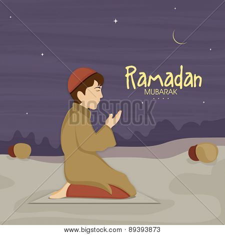 Cute little Muslim boy in traditional dress praying (reading Namaz, Islamic Prayer) in night on occasion of holy month Ramadan Kareem celebration.  