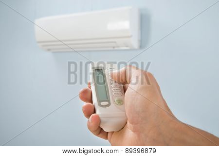 Man Adjusting Temperature Of Air Conditioner