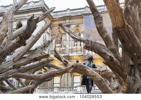 LONDON, UK - SEPTEMBER 23: Statue of Sir Joshua Reynolds framed by branches of Ai Wei Wei's installation 'Tree' in the forecourt of the Royal Academy of Arts. September 23, 2015 in London.
