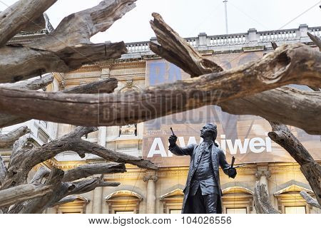 LONDON, UK - SEPTEMBER 23: Statue of Sir Joshua Reynolds framed by branches of Ai Wei Wei's installation 'Tree' in the forecourt of the Royal Academy of Arts. September 23, 2015 in London.