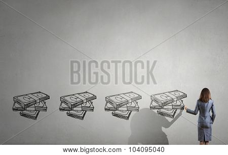 Back view of businesswoman drawing money banknotes on wall