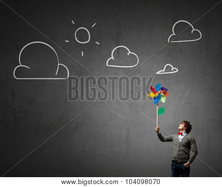 Young happy guy in casual with colorful windmill in hand
