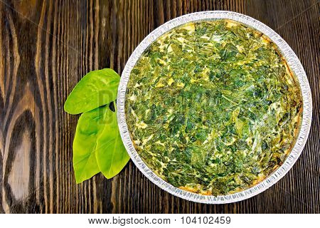 Pie celtic with spinach in form of foil on board
