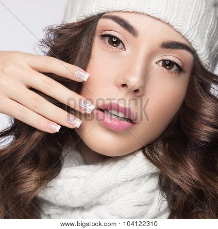 Beautiful girl with gentle makeup, design manicure and smile in white knit hat. Warm winter image. B