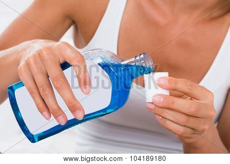 Woman Pouring Mouthwash Into Bottle Cap