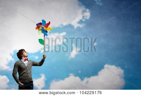 Young happy guy in casual with colorful windmill in hand