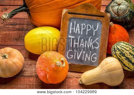 Happy Thanksgiving  - white chalk handwriting on a small blackboard surrounded by pumpkin and winter squash