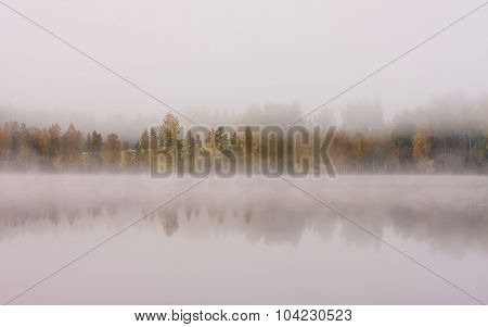 Foggy lake scape and vibrant autumn colors in trees