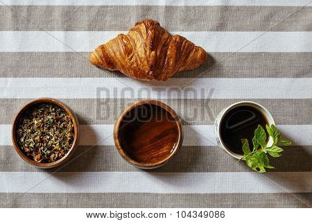 Croissant With Herbs And Honey And Cup Filled With Black Tea And Mint Top View