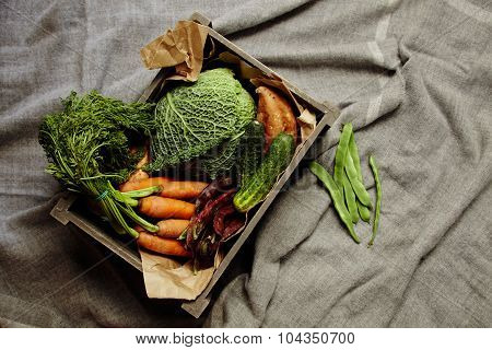 Harvest Of Vegetables In Wooden Box With Craft Paper On Rag Top View