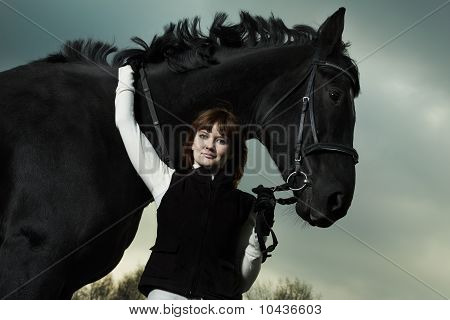 Hermosa joven con un caballo negro