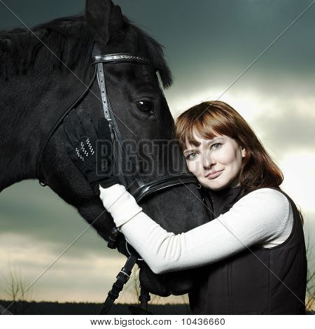 Hermosa joven con un caballo negro