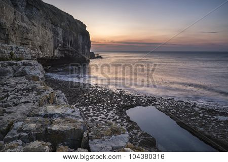 Stunning Coastal Landscape With Long Exposure Waves Crashing At Sunrise