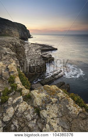 Stunning Coastal Landscape With Long Exposure Waves Crashing At Sunrise