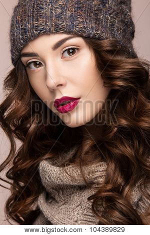Beautiful girl with gentle makeup, curls in brown knit hat. Warm winter image. Beauty face.