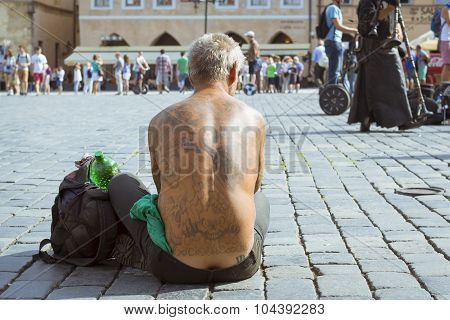 Naked beggar with a tattoo on her back
