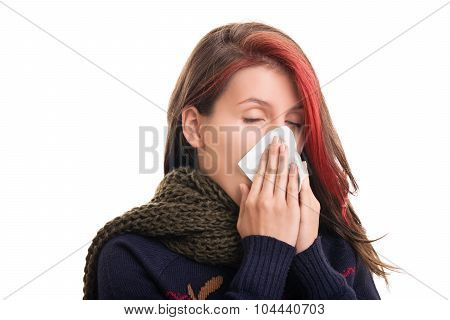 Cold and flu season. Portrait of a girl in winter clothes blowing her nose isolated on white background.