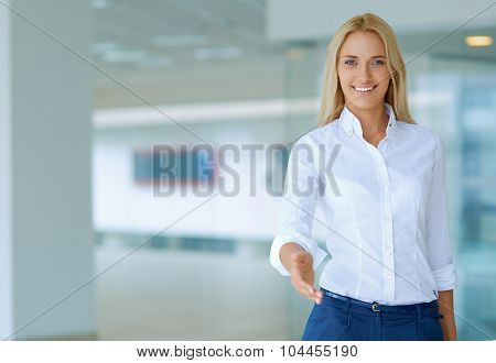 Young business woman ready to handshake standing in office