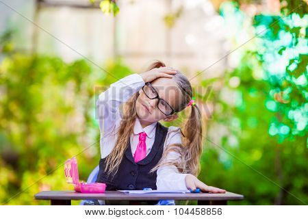 Adorable little school girl at desk with notes and pencils outdoor. Back to school.