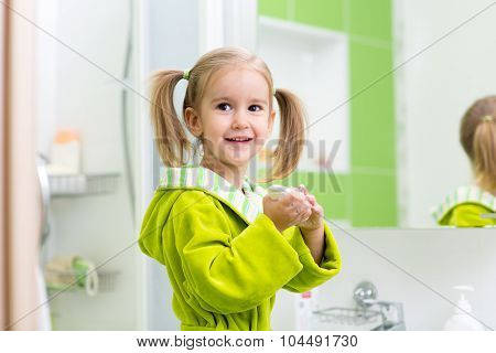 Cute little girl washing hands in bathroom