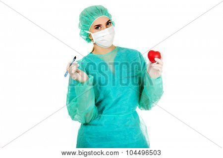 Young female cardiologist surgeron holding heart and scalpel.