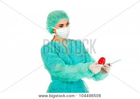 Young female cardiologist surgeron holding heart and scalpel.