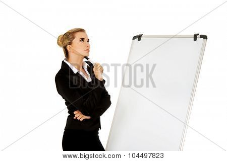Thinking business woman standing nex to the white board.