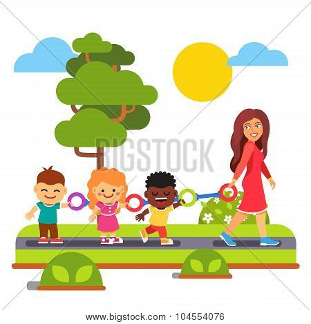 Kindergarten teacher walking with kids outdoors