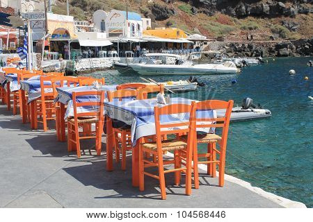 Greek Tavern With Orange Wooden Chairs By The Sea Coast, Greece, Santorini