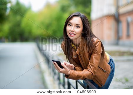Portrait Of A Young Beautiful Girl In The Urban Landscape. Young Urban Female Smiling Looking At Cam