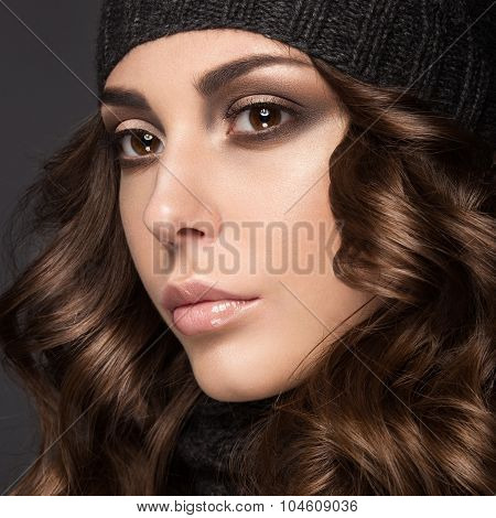 Beautiful girl with Smokeymakeup, curls in black knit hat. Warm winter image. Beauty face.