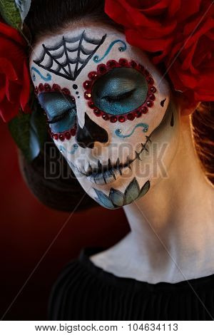 Closeup portrait of woman in santa muerte mask at halloween, eyes closed.