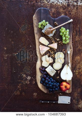 Wine appetizers set: French cheese selection, honeycomb, grapes, peach and walnuts on rustic wooden