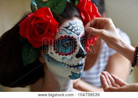 Makeup artists in work making a Halloween makeup - mexican Santa Muerte mask.