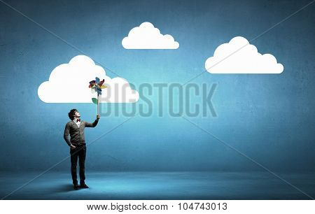 Young happy guy in casual with colorful windmill in hand