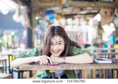Charming Asian Girl Sitting By Wooden Table And Reading Book