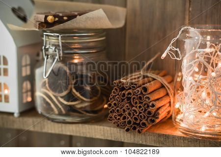Sweet home. White Christmas decor on vintage natural wooden background. Cinnamon sticks and dried citrus. Cafe shelf. Selective focus.