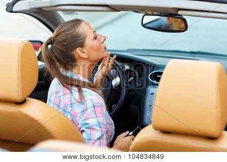 Woman Corrects Makeup Looking In The Rearview Mirror In A Convertible