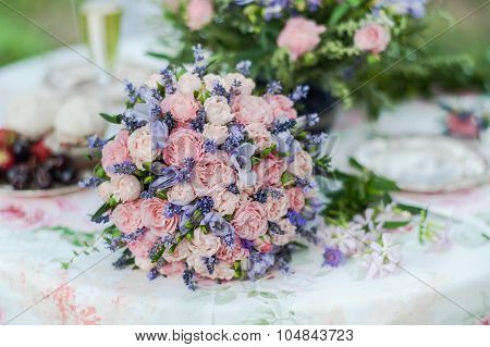 Served table outdoors. Flower arrangement with lavender and roses.