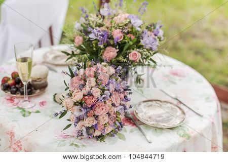 Served table outdoors. Flower arrangement with lavender and roses. Wedding decorations.