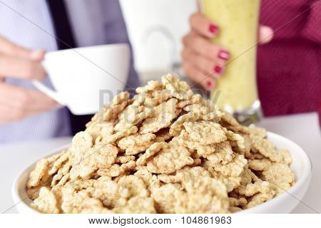 closeup of a young man and a young woman about to have coffee, oatmeal cereal and smoothie for breakfast at the kitchen table