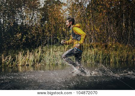 male runner crossing a mountain river, around him water splashes