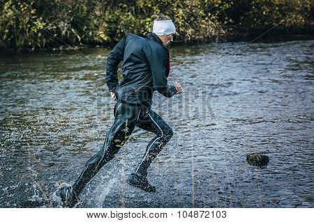 male athlete crossing the river on rocks side view