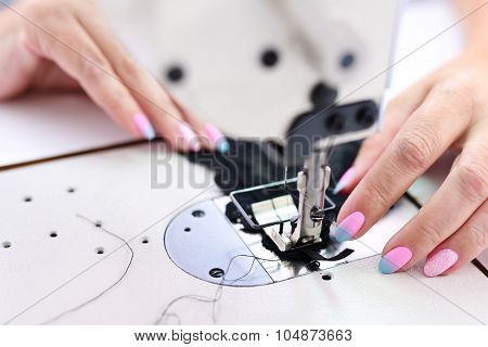 Seamstress sewing on the sewing machine in the manufacturing plant