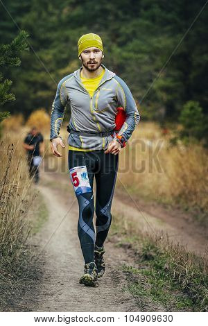 young male runner running through forest road
