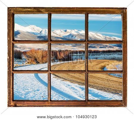 travel concept - a view of windy  road and snowy mountains  through vintage, grunge, sash window with dirty glass  - Medicine Bow Mountains, Colorado